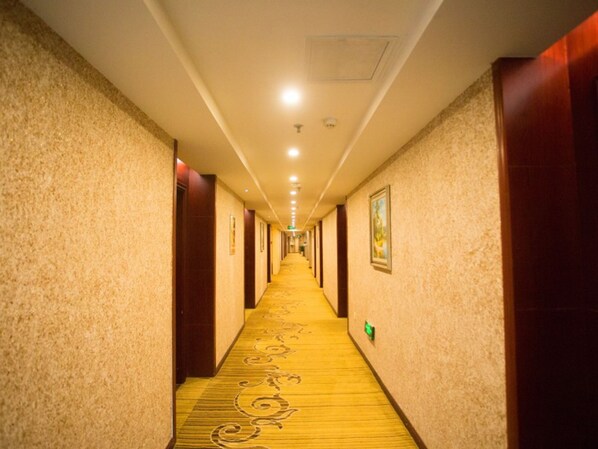 Ein Hotelkorridor mit Teppichböden, Holztüren und gerahmten Bildern an den Wänden.