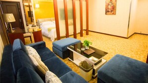 Ein Hotelzimmer mit einer Couch, einem kleinen Tisch mit einer Pflanze, einem Bett, einem Schreibtisch und einem Spiegel.