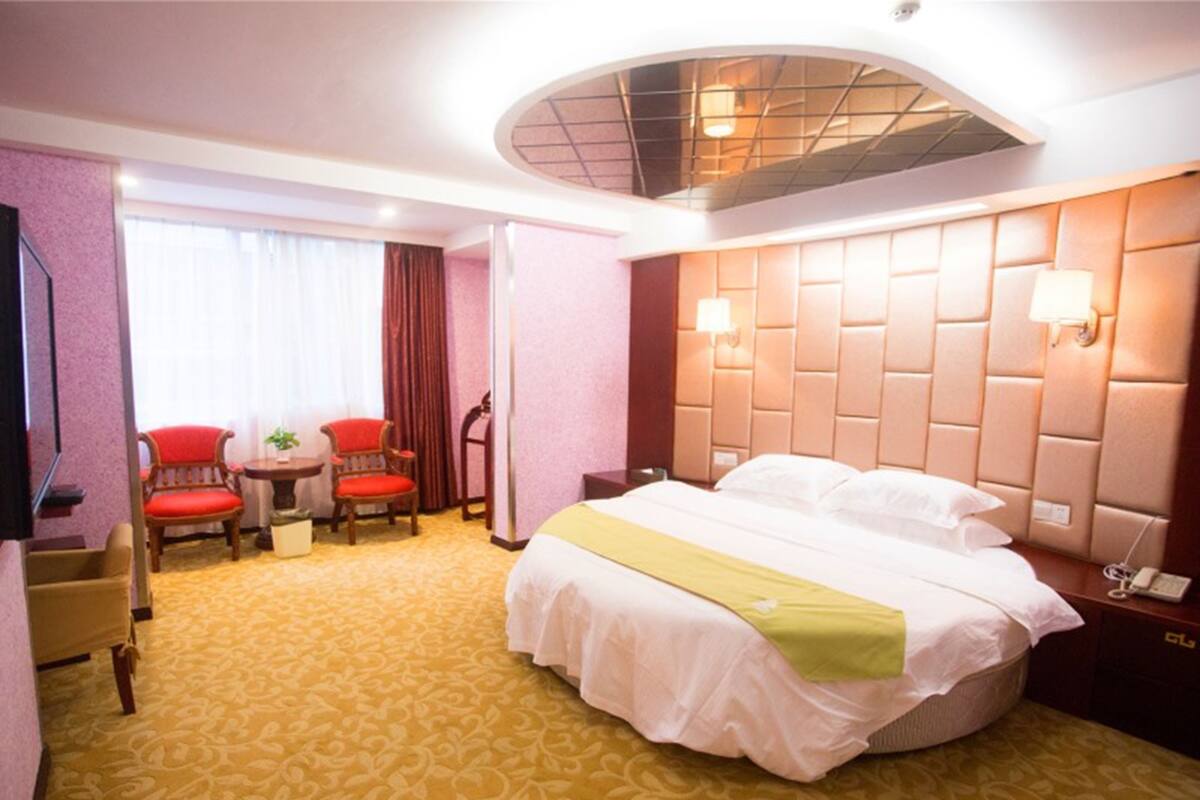 Habitació d'hotel amb un llit gran, una taula de treball, dues cadires, una taula petita i un televisor.
