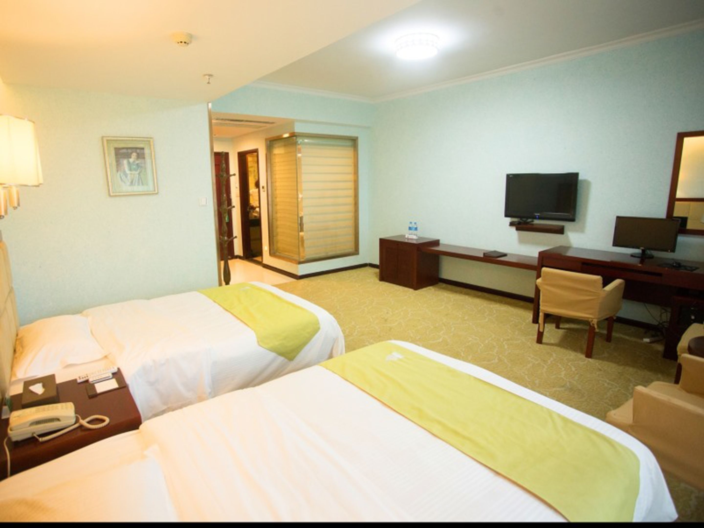 A hotel room with two beds, a desk with a computer, a TV, and a chair.