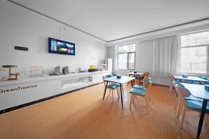 Un salón de conferencias con una larga mesa y sillas, un televisor montado en la pared y un ventanal que proporciona luz natural.