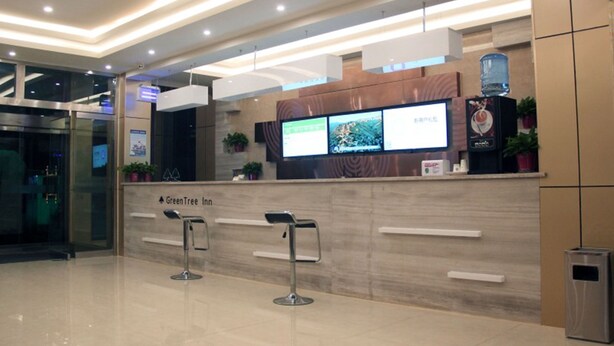 A reception area with a digital display, a water dispenser, and a trash bin. - GreenTree Inn Express Hotel (Binzhou Wudi Ancient City) (Binzhou)