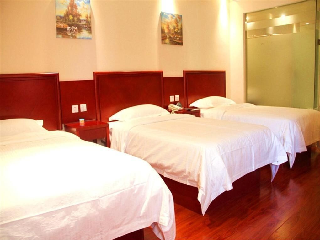 Ein Hotelzimmer mit drei Einzelbetten, Holz-Kopfteilen und einem großen Spiegel an der Wand.
