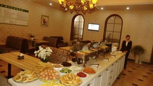 A buffet setup with various food items and a person standing by the counter. - GreenTree Inn LinYi Lanshan District LinXi No.11 Road Express Hotel (Linyi)