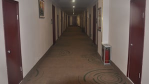 A long, narrow hotel corridor with doors on both sides, a fire extinguisher on the right, and a carpet with circular patterns. - GreenTree Inn LinYi Lanshan District LinXi No.11 Road Express Hotel (Linyi)