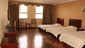 A hotel room with two beds, a desk, a chair, and a small table.