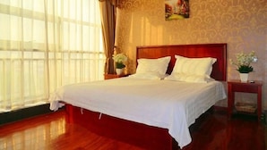 A large bed with white linens, a wooden headboard, and a floral arrangement on the nightstand. - GreenTree Inn LinYi Lanshan District LinXi No.11 Road Express Hotel (Linyi)
