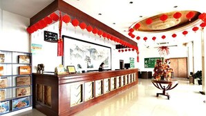 A reception area with a wooden counter, framed artwork, and red lanterns. - GreenTree Inn Lianyungang Ganyu South Station Express Hotel (Lianyungang)