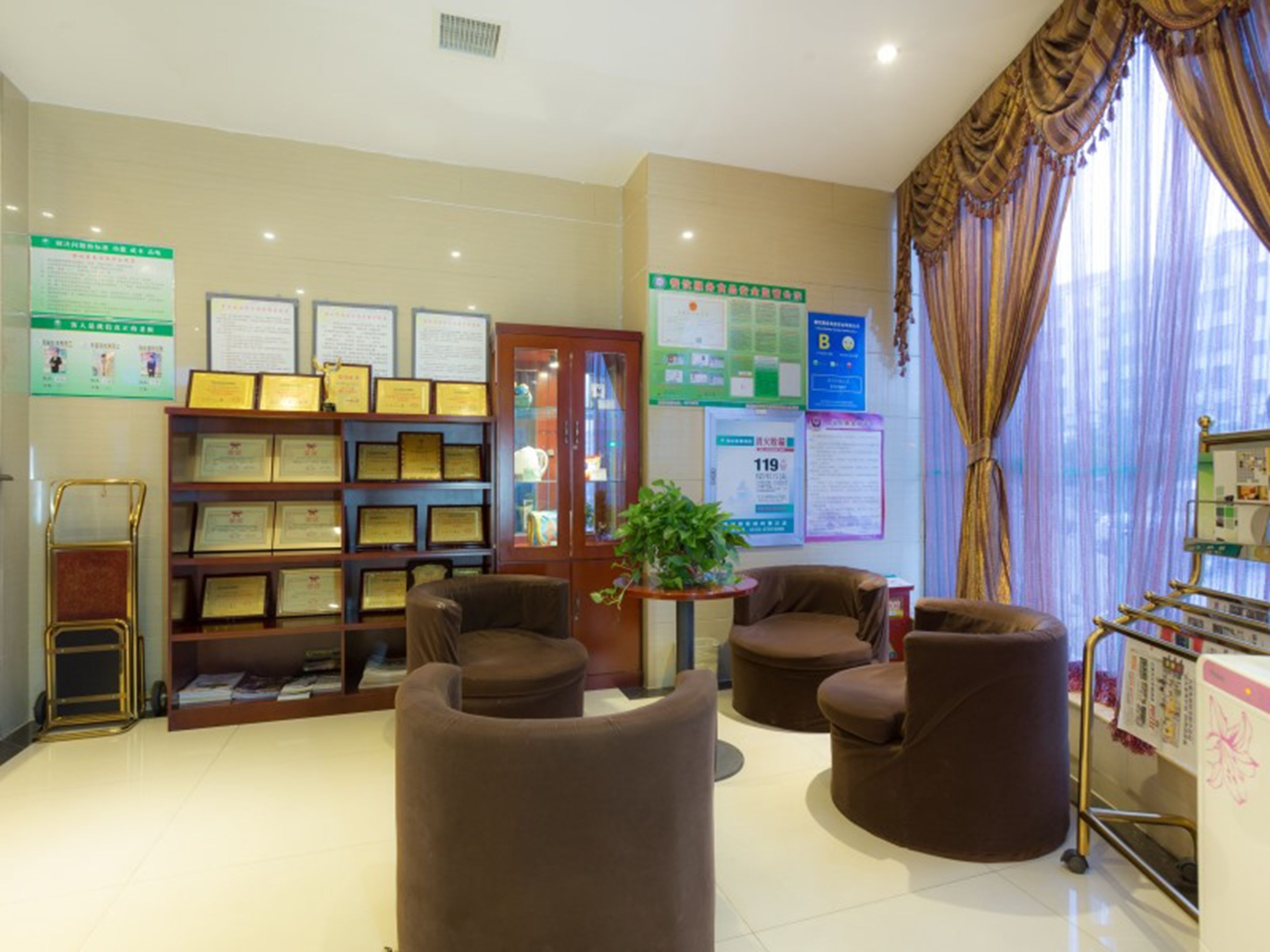 A reception area with a bookshelf displaying certificates, a potted plant, and a seating area with armchairs.