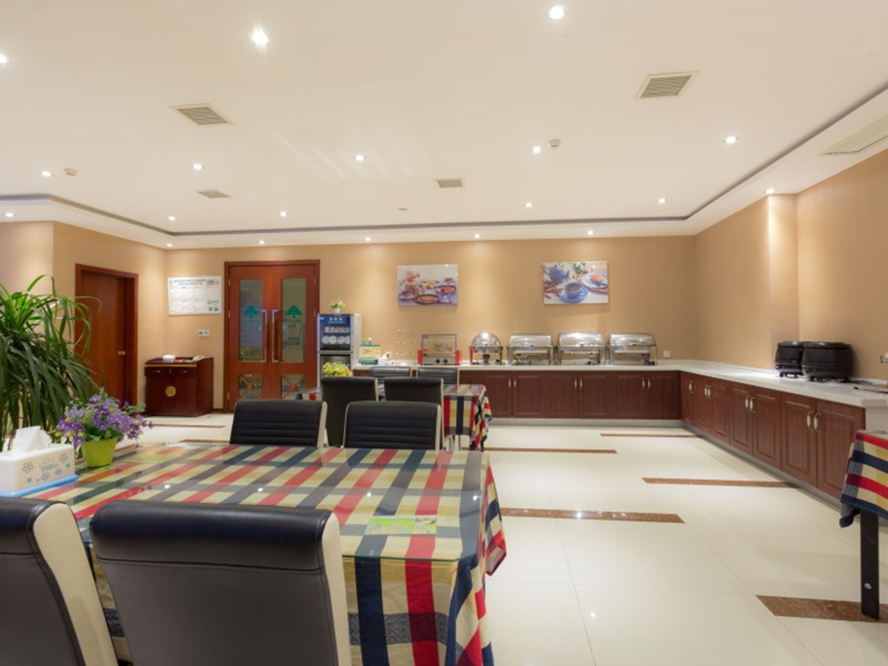 Un espace de restauration d’hôtel comprenant un buffet, des tables et des chaises, ainsi qu’un comptoir d’accueil.