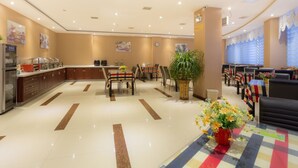 A hotel lobby with a reception desk, seating area, and a buffet.
