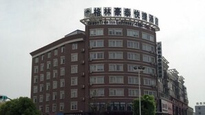 A multi-story hotel with a curved facade, multiple windows, and a sign indicating it is a GreenTree Inn.