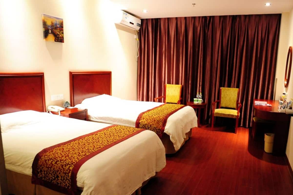 A hotel room with two beds, a desk, a chair, and a large window with curtains.