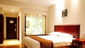 A hotel room with a large bed, a wooden headboard, a bedside table, and a large mirror.