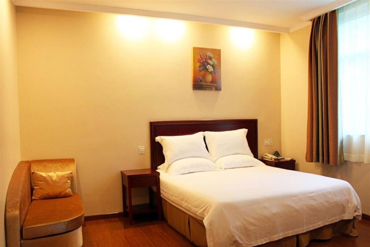 Ein Hotelzimmer mit einem großen Bett, einem Nachttisch, einem Sessel und einem Bild an der Wand.