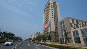 A multi-story hotel with a modern design, featuring a prominent green logo on the facade. - GreenTree Inn GuangDe County ZhongYang LeCheng Hotel (Xuancheng)