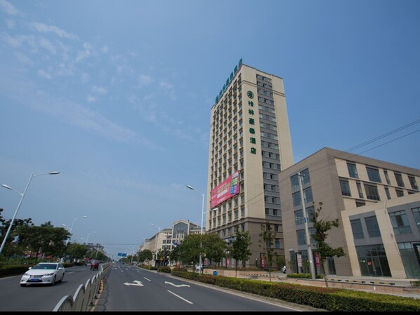 A multi-story hotel with a modern design, featuring a prominent green logo on the facade. - GreenTree Inn GuangDe County ZhongYang LeCheng Hotel (Xuancheng)