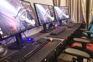 Configuración para videojuegos con tres monitores, dos teclados y un ratón.