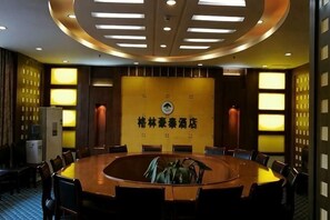Una sala de conferencias con una mesa redonda, sillas y una pared con un logotipo.