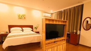 Une chambre d’hôtel avec un lit, une télévision, une armoire en bois et un miroir.