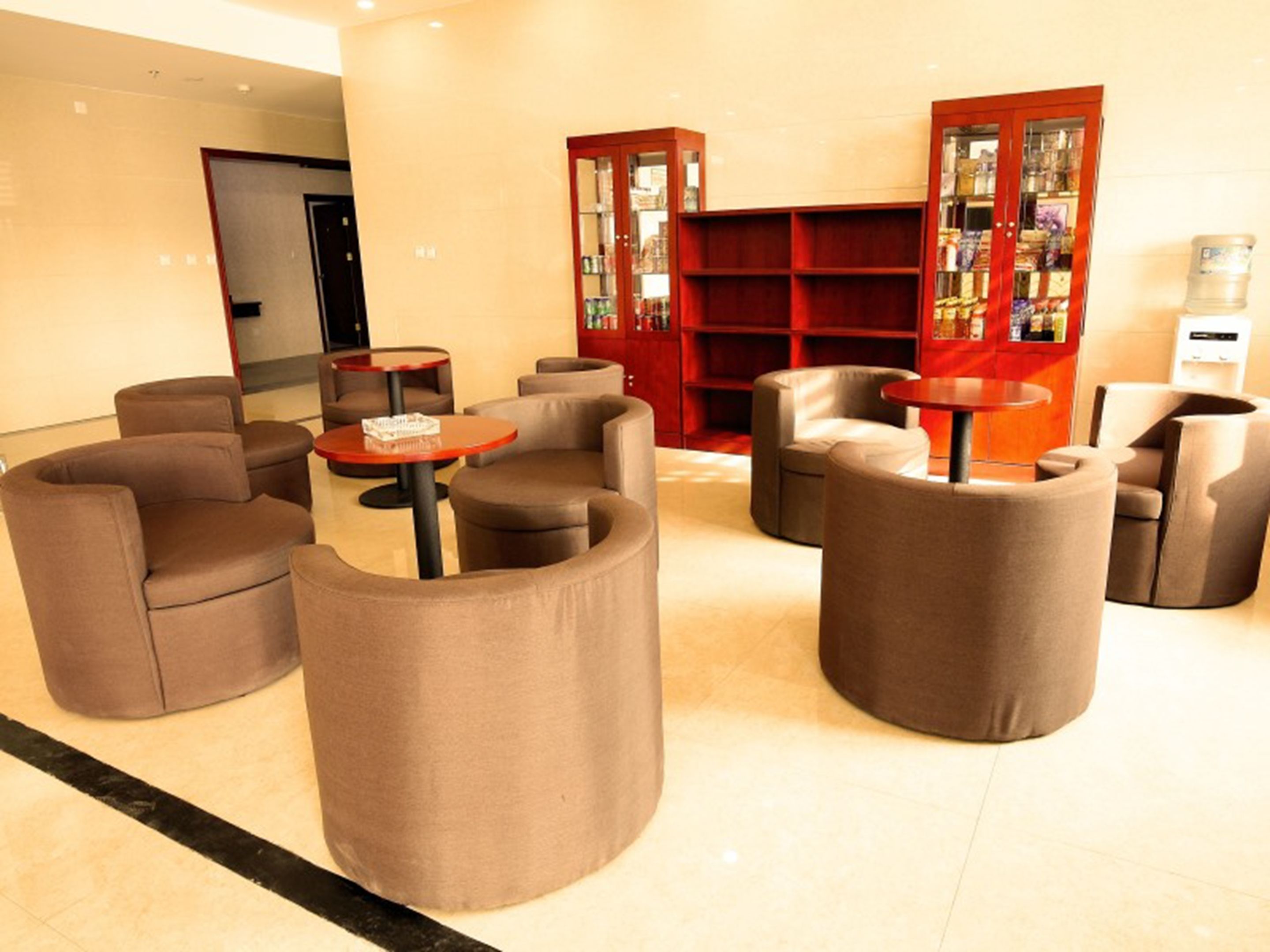 Um lobby com áreas de estar circulares, uma estante vermelha e uma mesa de recepção.