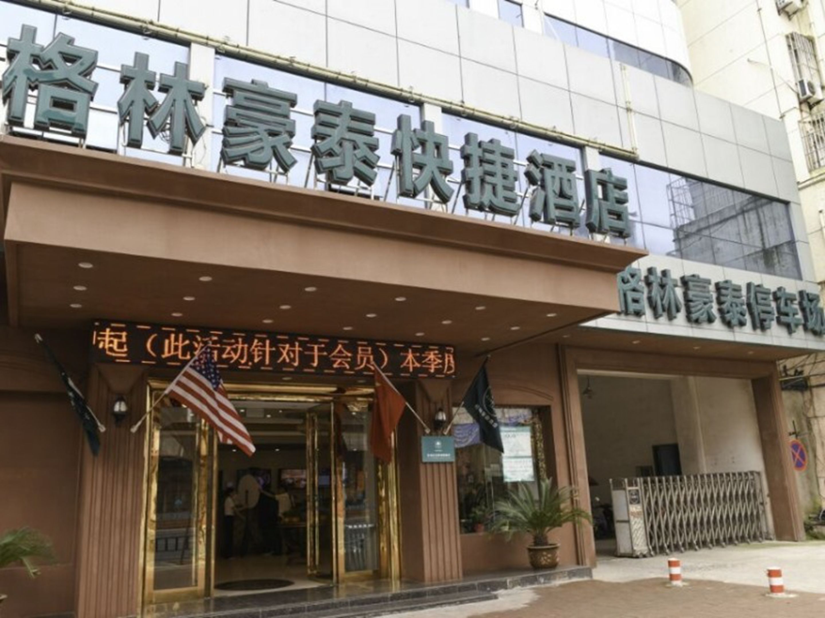 A hotel entrance with a sign in Chinese characters, an American flag, and a sign indicating a special event or promotion.