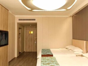 A hotel room with a bed, a television on the wall, and a door leading to another room.