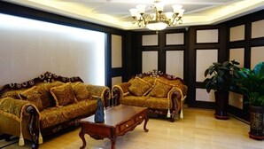 A room with two ornate sofas, a wooden coffee table, and a chandelier. - GreenTree Inn LiaoYuan Longshan District Train station Longjihuadian Hotel_ (Liaoyuan)