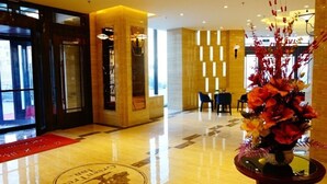 A hotel lobby with a polished floor, a reception desk, and a decorative vase with flowers. - GreenTree Inn LiaoYuan Longshan District Train station Longjihuadian Hotel_ (Liaoyuan)