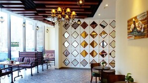 A spacious cafe with a modern interior, featuring a patterned floor, wooden ceiling beams, and a wall decorated with diamond-shaped mirrors. - GreenTree Inn LiaoYuan Longshan District Train station Longjihuadian Hotel_ (Liaoyuan)