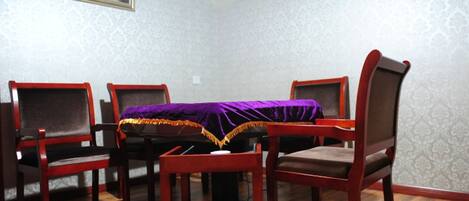A dining room with a table covered by a purple cloth, surrounded by wooden chairs with cushioned seats.