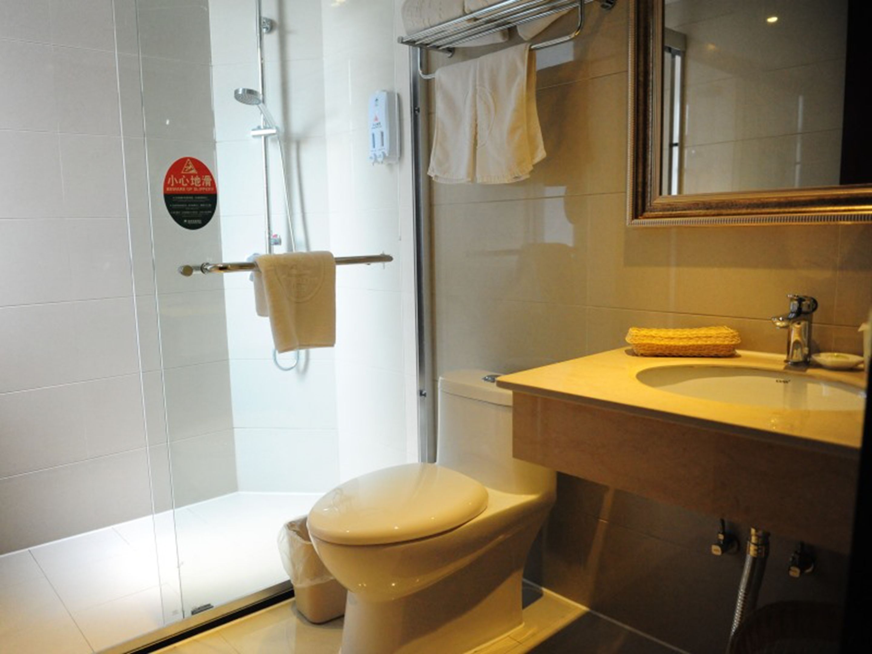 A bathroom with a toilet, a sink, a shower, and a towel rack.