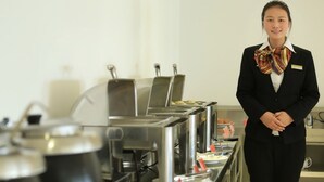 A person standing in a kitchen area with stainless steel appliances and a buffet setup. - GreenTree Inn Suqian Suyang South ShangHai Rd Darunfa Hotel (Suqian)