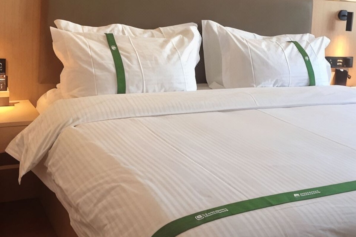 Une chambre d’hôtel avec un lit bien fait, une tête de lit et une table de chevet avec une lampe.