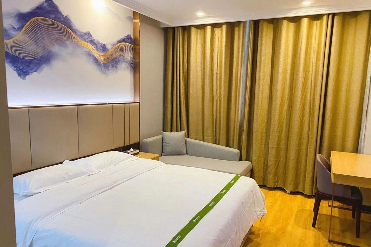 Une chambre d’hôtel avec un grand lit, un canapé, un bureau et un tableau au mur.