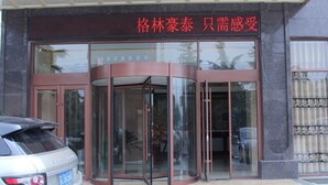 A hotel entrance with a revolving door and a car parked in front. - GreenTree Inn XuZhou PiZhou Dayunhe Decorative city  PiXin N Road Express Hotel (Xuzhou)