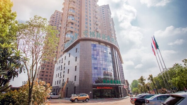 A high-rise building with multiple floors, featuring a curved glass facade and a sign with Chinese characters. - GreenTree Inn HuaiAn KangJian W Road XiAn Road Hotel (Huai'an)