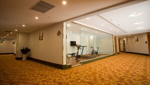 A hotel lobby with a carpeted floor, a glass wall with exercise equipment, and a ceiling vent. - GreenTree Inn HuaiAn KangJian W Road XiAn Road Hotel (Huai'an)