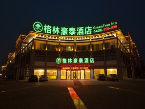 A hotel with a prominent GreenTree Inn sign, multiple floors, and a well-lit entrance. - GreenTree Inn TaiZhou JingJiang ZhongZhou Road Sunshine International Business Hotel (Taizhou)