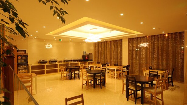 A restaurant with multiple dining tables and chairs, a bar area, and a ceiling light fixture. - GreenTree Inn TaiZhou JingJiang ZhongZhou Road Sunshine International Business Hotel (Taizhou)