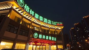 A hotel with a prominent sign for GreenTree Inn, featuring a contact number and a logo. - GreenTree Inn TaiZhou JingJiang ZhongZhou Road Sunshine International Business Hotel (Taizhou)