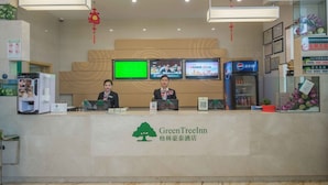 A reception desk with two staff members, a digital screen, and a Pepsi refrigerator.