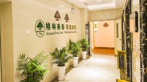 A hallway with a GreenTree Inn sign, potted plants, and a marble floor.