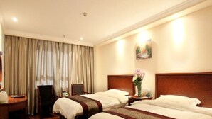 Ein Hotelzimmer mit zwei Betten, einem Schreibtisch, einem Stuhl und einem großen Fenster mit Vorhängen.