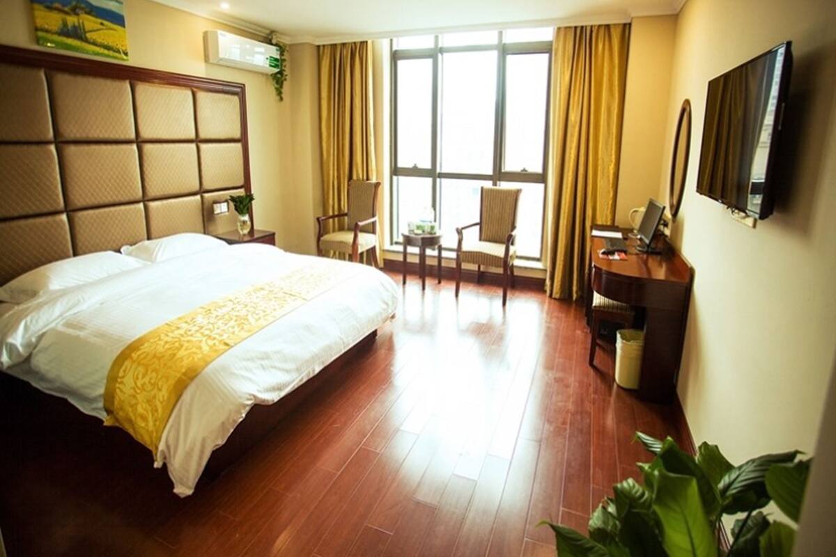 A hotel room with a large bed, a desk, a chair, and a TV.