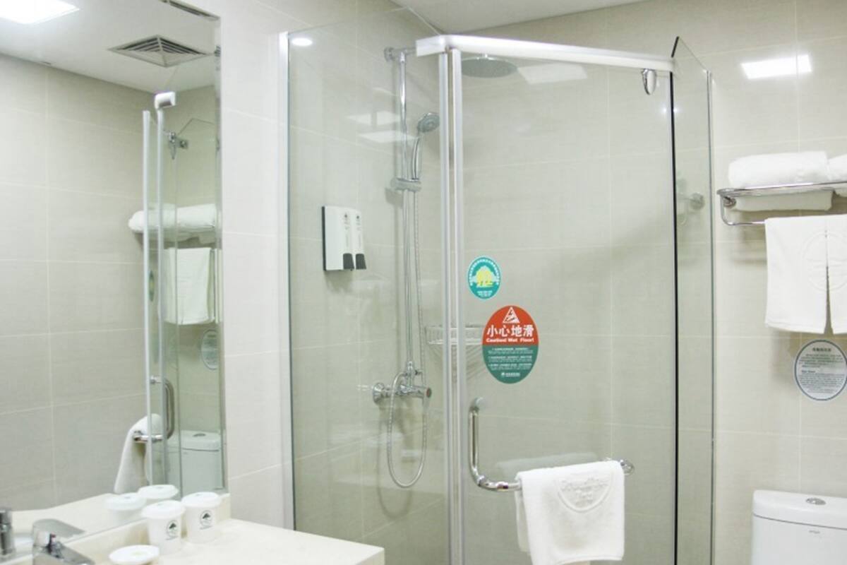 Een moderne badkamer met een glazen douchecabine, een wastafel met toiletartikelen en een toilet.