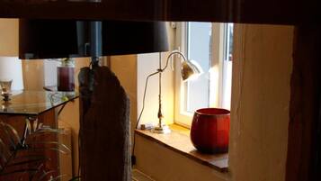 Et rustikt interiør med en træbjælke, en oksefigur, en lampe og et vindue med gardiner.