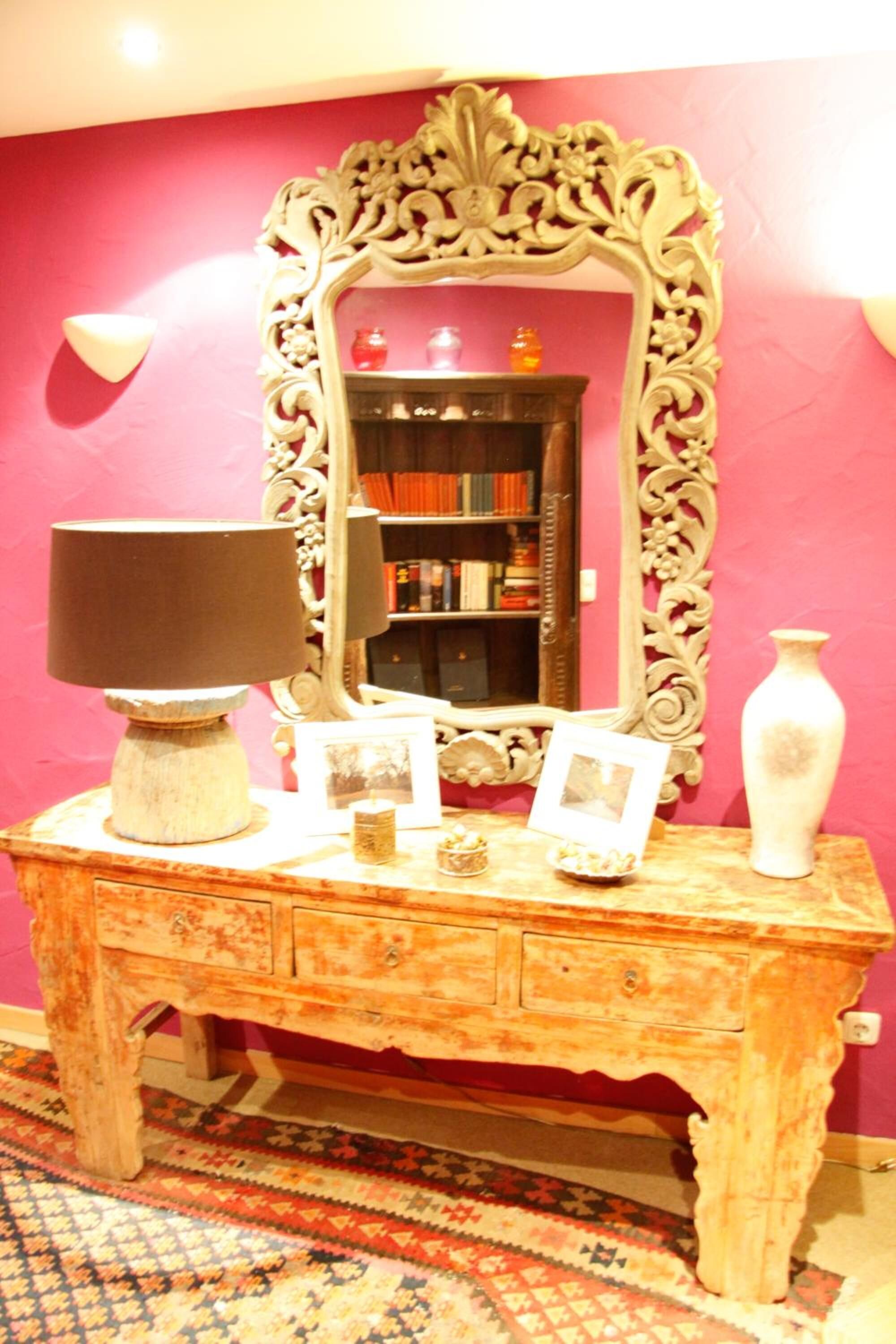 A vintage wooden desk with a lamp, framed photos, and a vase.