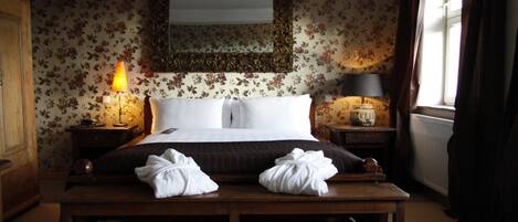 A bedroom with a bed, two bedside tables with lamps, a bench, and a large mirror above the bed.