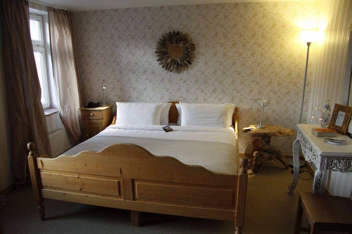 Et soveværelse med en træseng, et natbord, en lampe, en kommode og en vægdekoration.